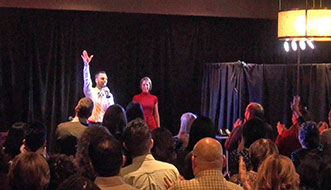 An enthusiastic audience of Revlon employees shows their appreciation for Aaron Paterson's corporate entertainment by giving him a standing ovation.
