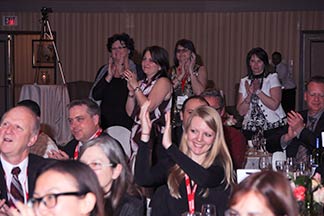 Audience members stand and applaud for Event                                    Entertainment performer Aaron Paterson.